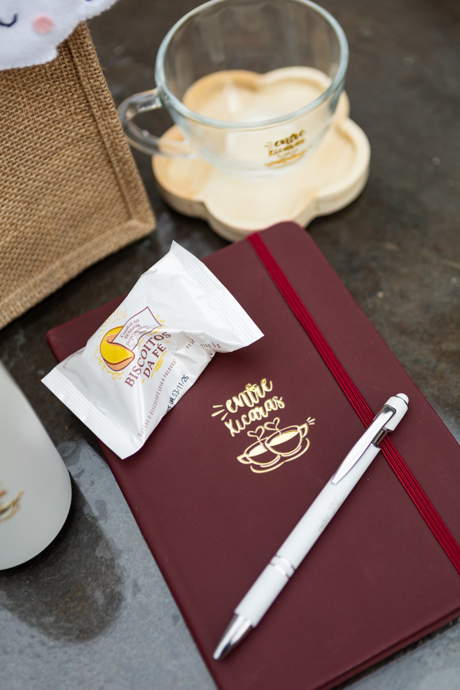 Xícara de café e caderno do Entre Xícaras sobre a mesa